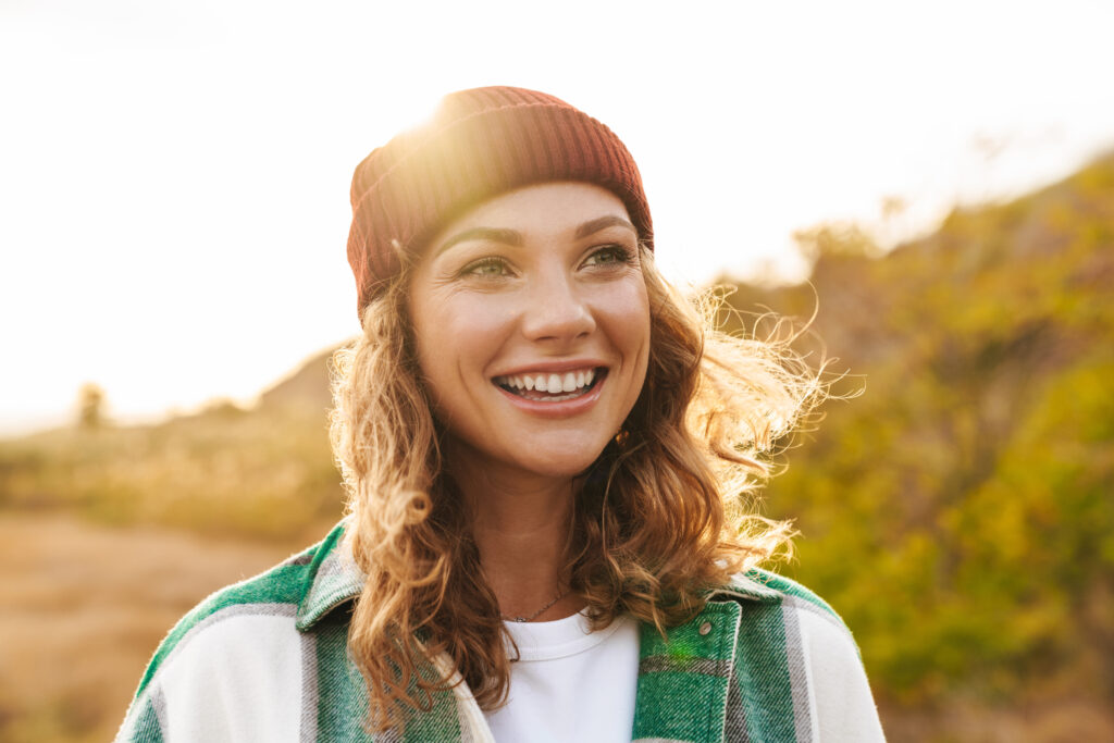 Image of young woman wearing hat and plaid shirt walking outdoor